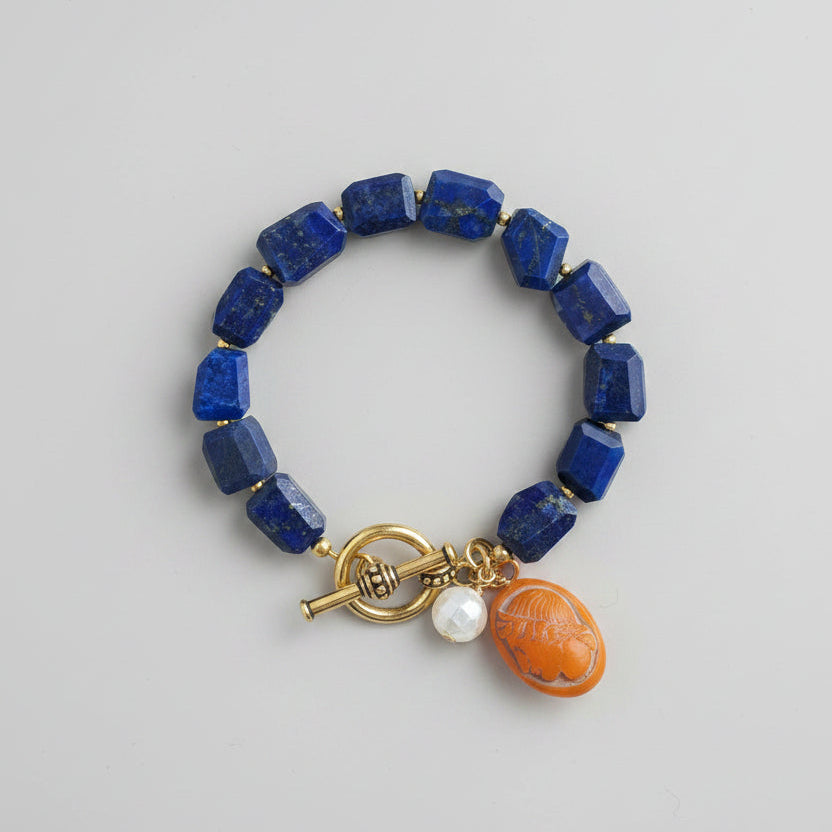 Blue beaded bracelet with a gold charm on a wooden surface